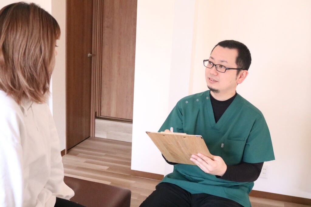 整骨院で保険が使えない症状に対して説明する交野エニフ整骨院の施術スタッフ